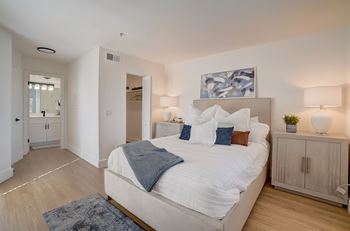A bedroom with a large bed, a nightstand, and a painting on the wall.